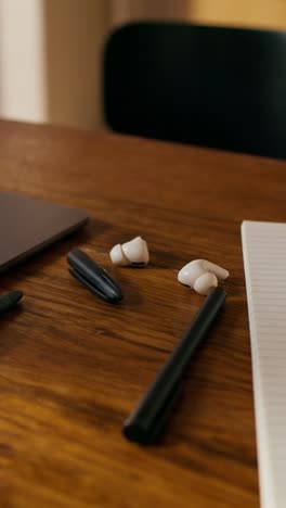 work desk with laptop, pen, and earbuds