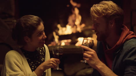 couple celebrate evening date by fireplace. relaxed lovers enjoy drink wine.