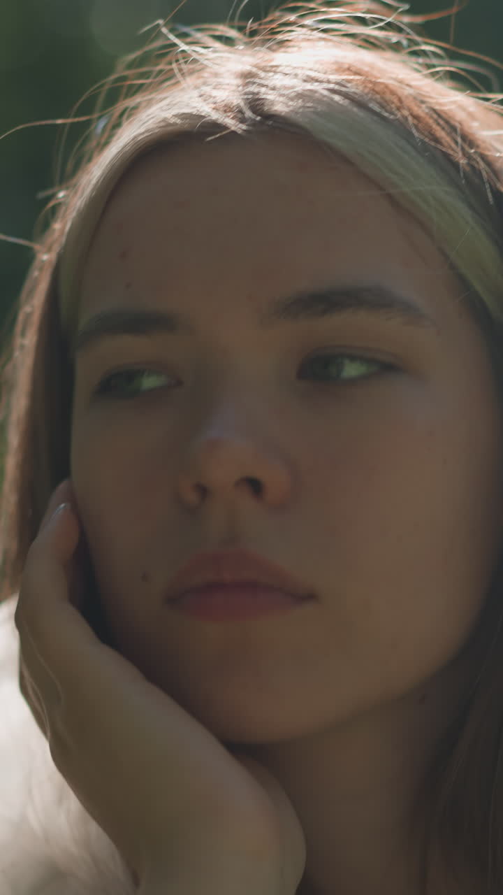 primer plano de una mujer joven con un impermeable translúcido bajando la capucha con la mano izquierda, con un reloj inteligente y mirando contemplativamente a la distancia