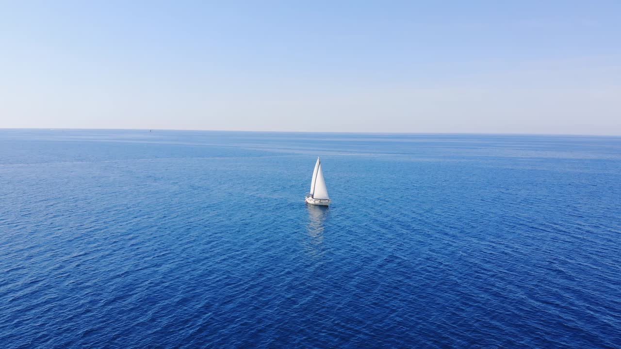 Aerial: bird's eye view of one sailing boat cruising in the open sea or ocean