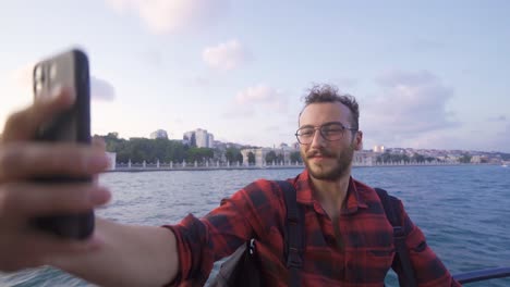un joven tomando una selfie con el teléfono en el ferry.