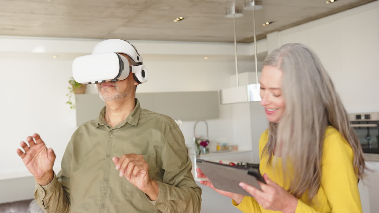 Using VR headset, man interacting while woman holding tablet and smiling, at home