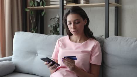 mujer que usa una tarjeta de crédito con un teléfono inteligente hace que la compra se sienta satisfecha