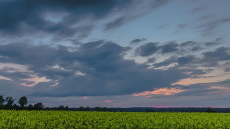 Increíble-Lapso-De-Tiempo-Con-Toma-En-Movimiento-Sobre-Un-Campo-Con-La-Puesta-De-Sol-En-El-Horizonte-Y-Clous-Moviéndose-En-El-Cielo