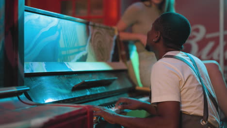 positive pianist plays music to impress woman at party. african american musician performs melody while girlfriend listens in night club. musical show