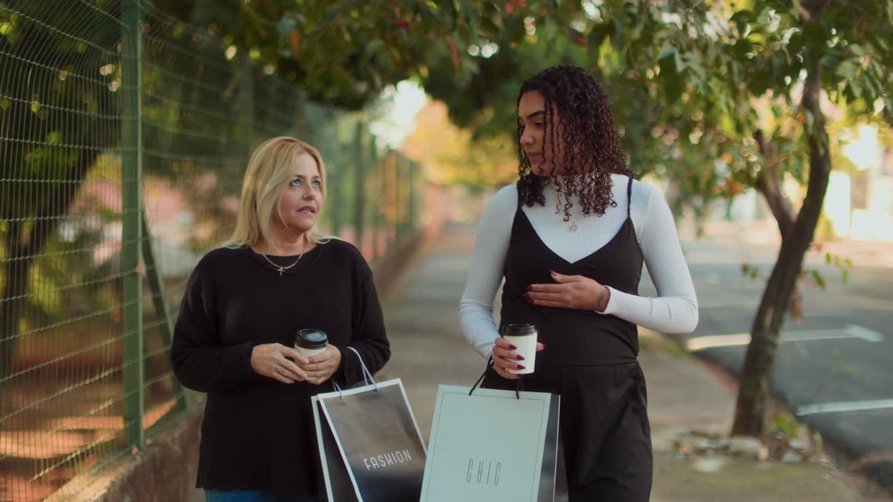 Two friends walking and chatting with shopping bags and coffee