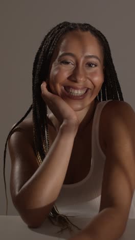 studio beauty shot of young woman with long braided hair sitting at table 3