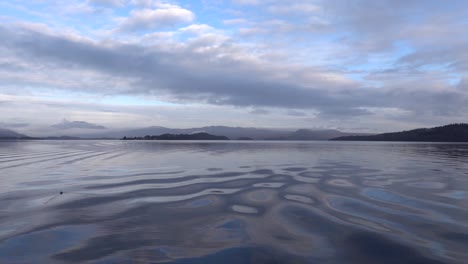 blue sky above the calm waters of loch lomond scotland