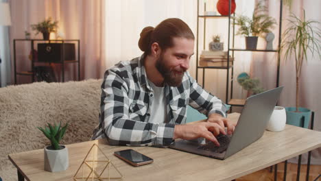 young man man opens laptop at home wow great winning result in an online course celebrates victory