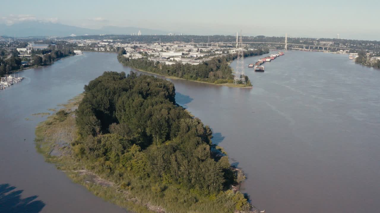 Aerial Fly over an island indangered wild life in the midst of big industry import export harbor for freighters barges cargo for natural resources hemp lumber produce canibas a river ocean connect 1-3