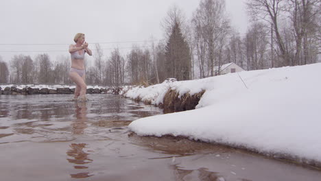 Una-Mujer-Bañándose-En-Hielo-Suena-Sus-Guantes-Mientras-Sale-Del-Agua-Helada,-Cámara-Lenta