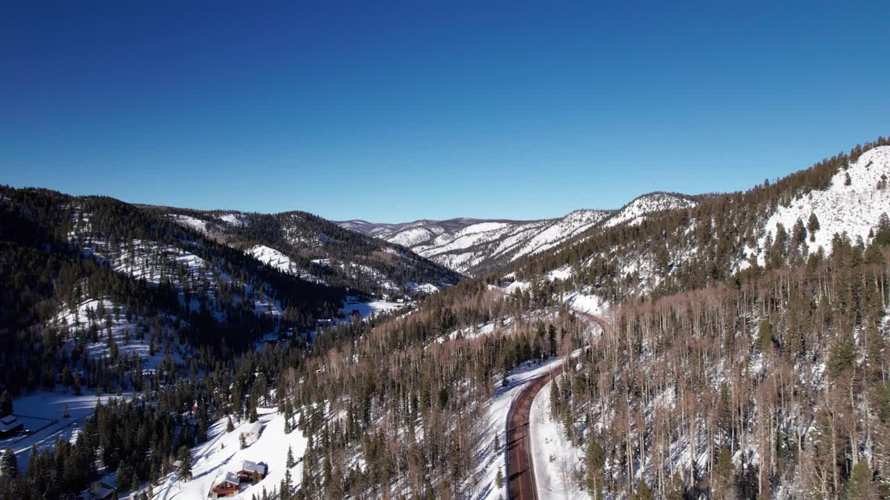 Drone shot revealing a highway in the snow covered mountains.