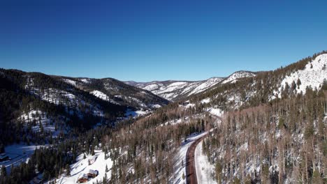 drone shot revealing a highway in the snow covered mountains.