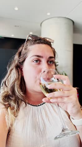 woman holding a glass of white wine while vlogging