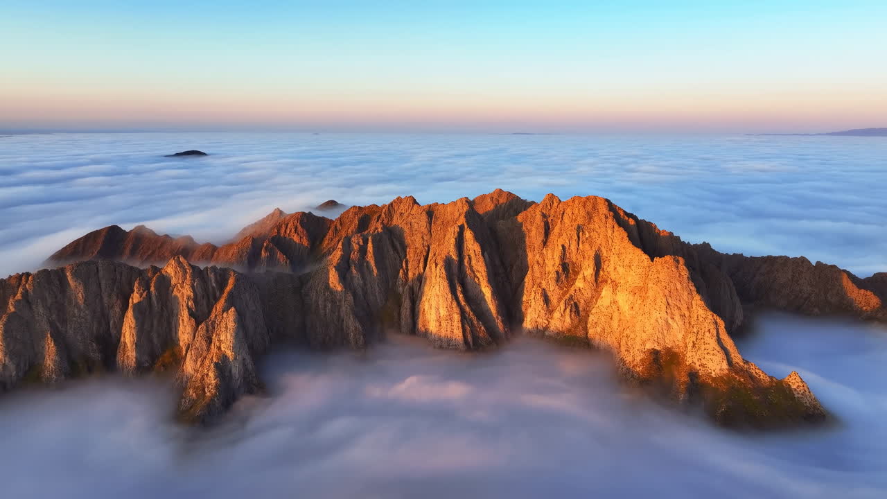 Resplandor Alpino en Picos Montañosos Cubiertos de Nubes Proyectando un Brillo Cálido, Acantilados Irregulares Elevándose Sobre un Mar de Nubes Interminable