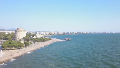 The-Wonderful-White-Tower-In-Thessaloniki-Greece-Infront-Of-A-Deep-Blue-Ocean-During-Daytime---Aerial-Shot