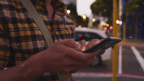 using smartphone, person standing on busy city street with blurred lights