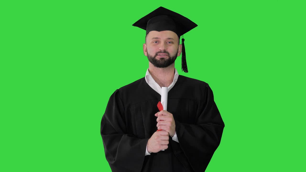 Giovane uomo felice con cappello da laureato che tiene in mano il diploma e parla su uno schermo verde, Chroma Key