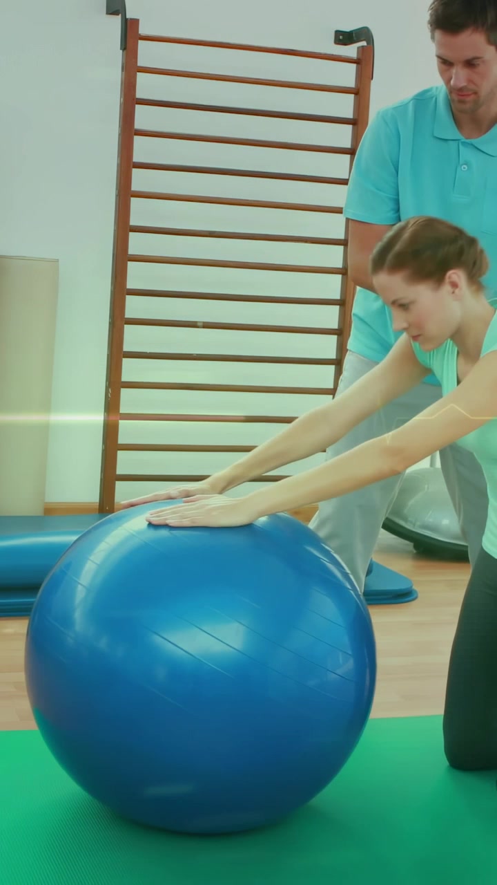 Vertikales Video: Klient legt Unterarme auf blauen Ball, Therapeut leitet Haltung für die Reha an.