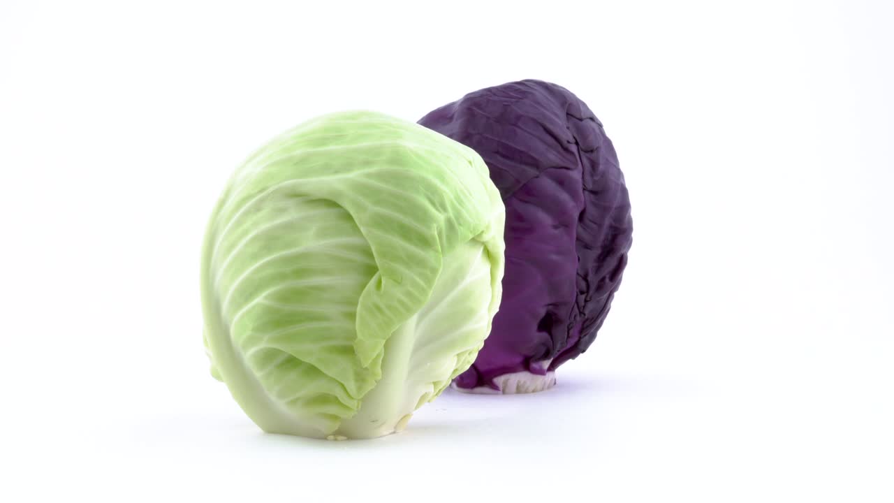 dos mini repollo entero, blanco y rojo están girando en la mesa giratoria aislados en el fondo blanco. primer plano. macro.