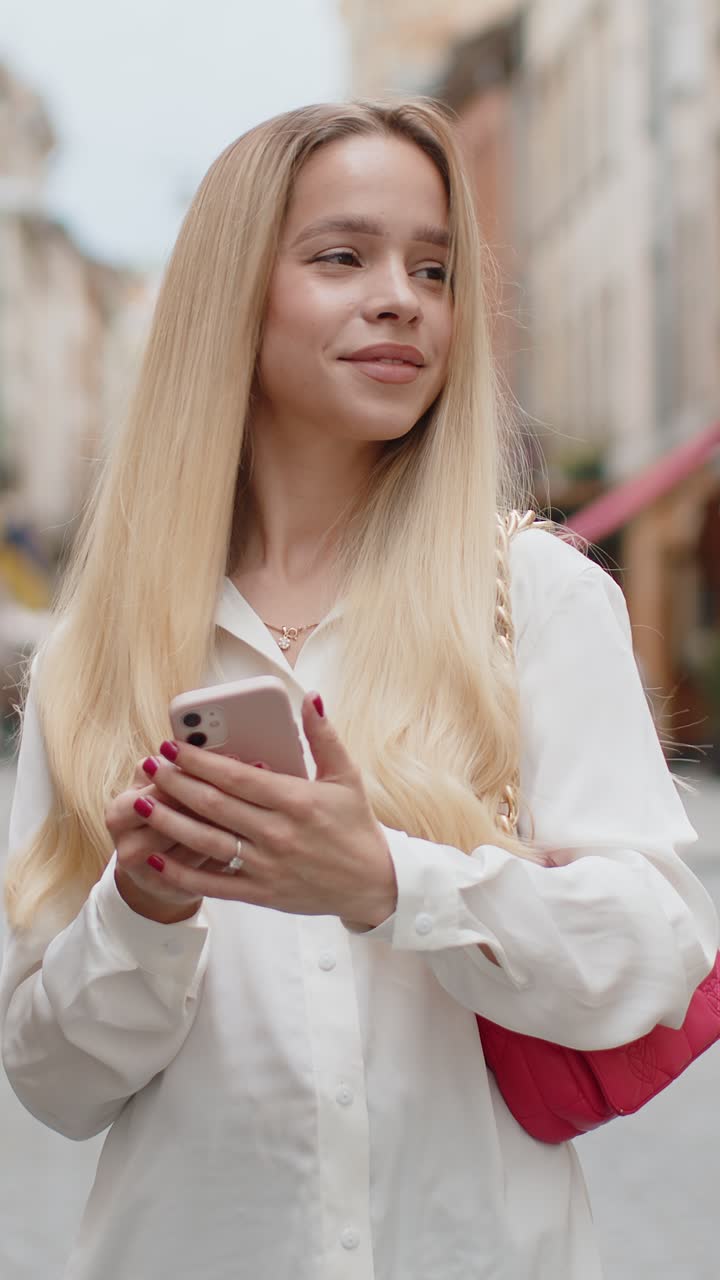 Young woman use smartphone typing text messages browsing internet finishing work looking at camera
