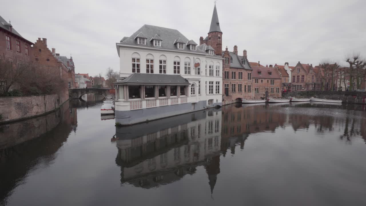 hotel y restaurante duc de bourgogne con reflejo especular en aguas tranquilas del canal dijver en brujas, bélgica