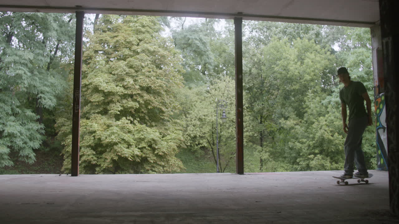 백인 소년이 폐허가 된 건물에서 스케이트보드를 타고 있습니다.