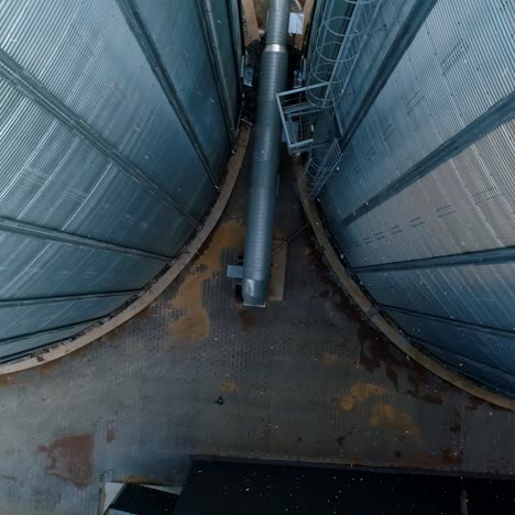 large metal hangar. grain elevators outdoors. aluminum containers for storing grain. agribusiness. modern industrial plant. motion down.