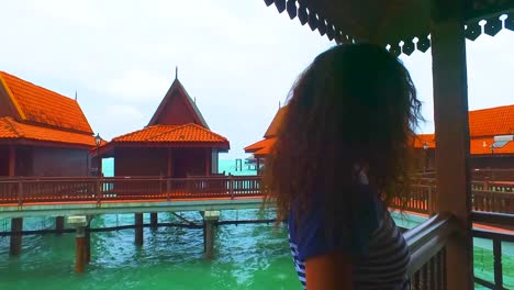 a woman relaxed on a stilt house of a luxury hotel looks at the sea in the island of langkawi