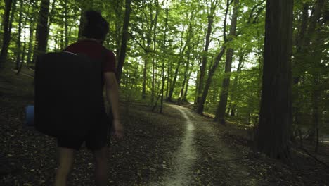 a young latino is walking a forest path alone with a yoga mat in his hands