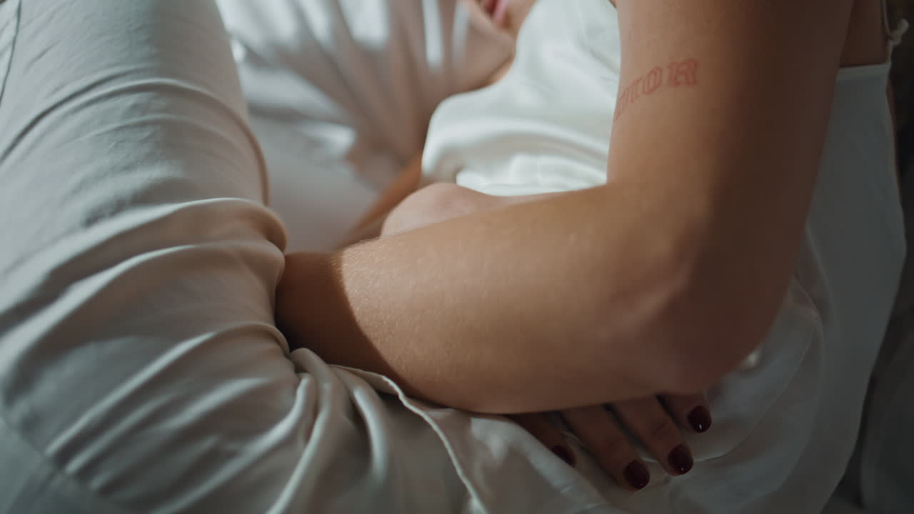 Person touching stomach ache lying in bed closeup. Girl hands on painful belly