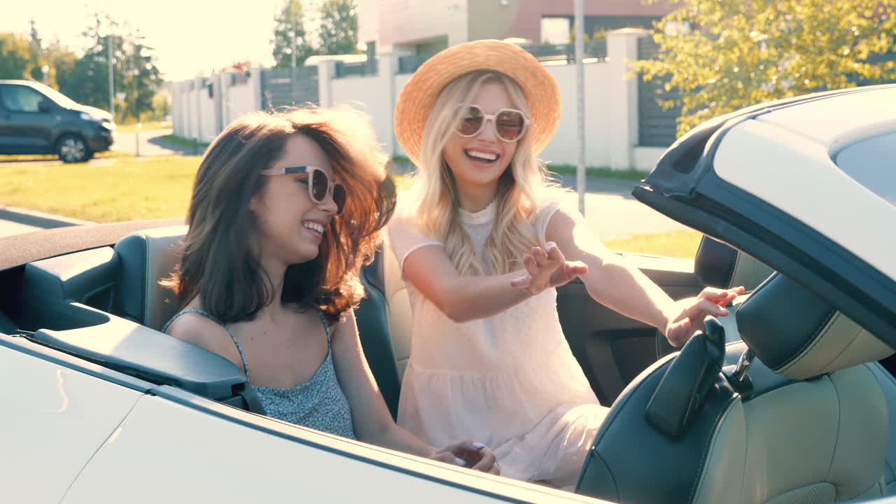 dos mujeres felices disfrutando de un viaje por carretera de verano en un descapotable