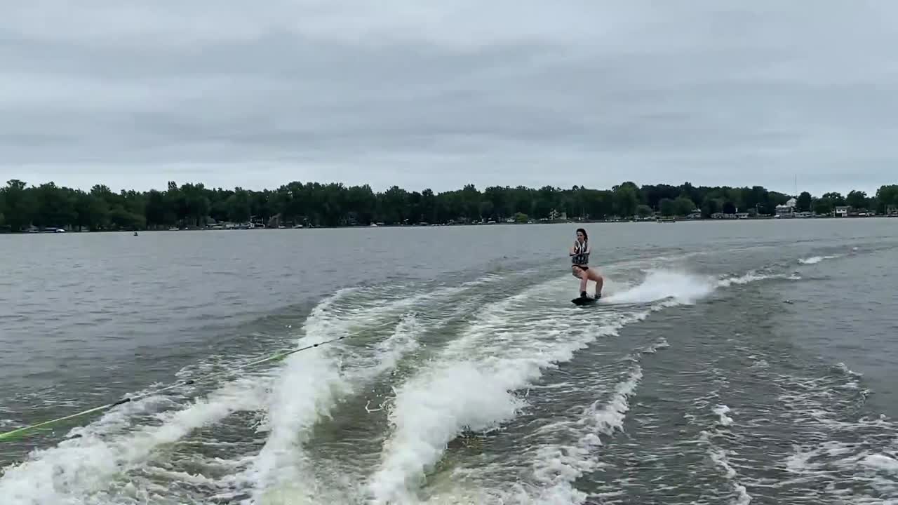 Person wakeboarding behind boat at a lake