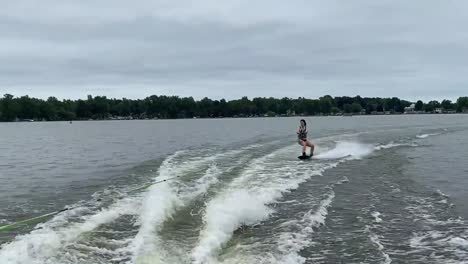 person wakeboarding behind boat at a lake