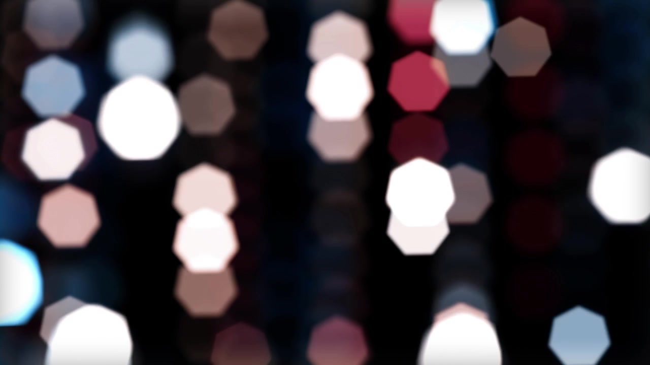 Luci Bokeh Esagonali Dinamiche in Movimento su Sfondo Nero