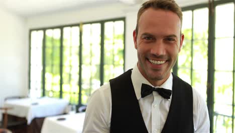 smiling waiter holding tray with glasses of red wine