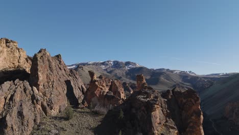 drone slow climb over rock formations at leslie gulch oregon to reveal rock pinnacles and snow capped mountains