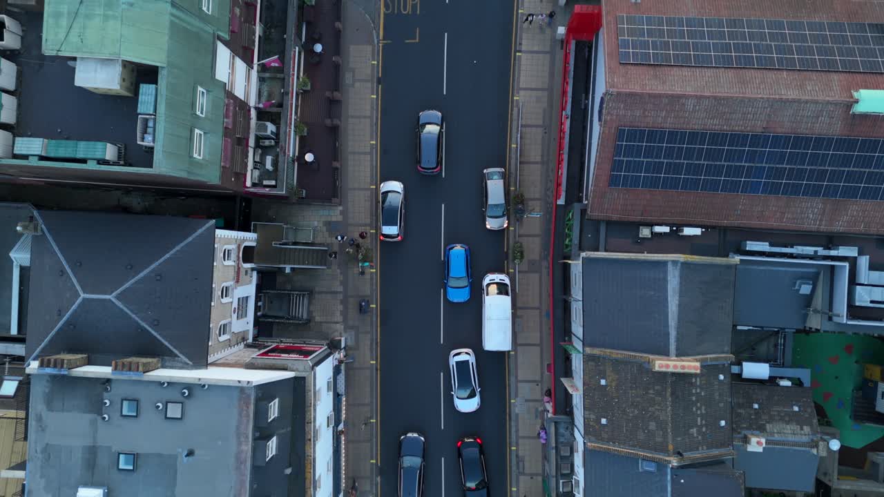 Birds eye view drone hyperlapse narrow city high street with cars and shops in England