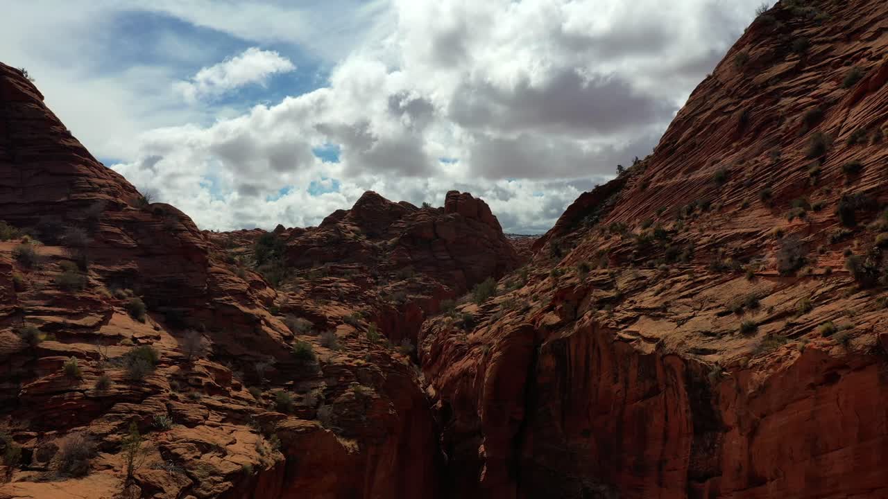 Drone flying low inside a red rock slot canyon