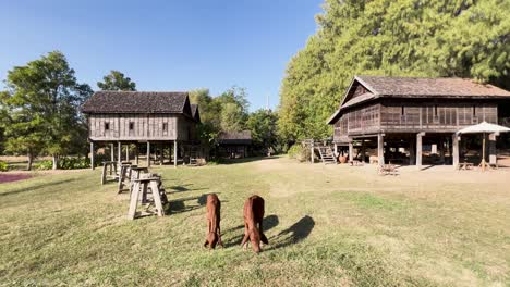 a cow grazes near a traditional thai house