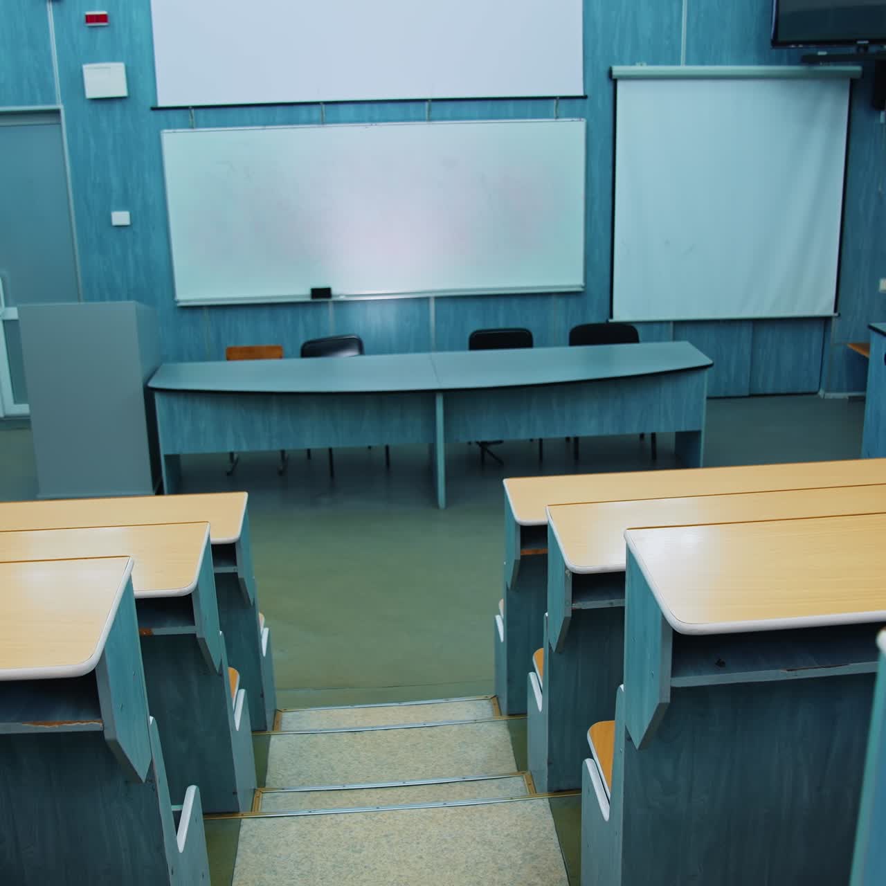 Empty auditorium. Modern lecture hall in the university. Wooden desks in front of blackboard and multimedia board in conference hall