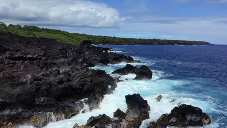 Luftaufnahme-Der-Küste-Hawaiis-Mit-Schwarzem-Vulkangestein,-Brechenden-Wellen-Und-üppiger-Grüner-Vegetation-Unter-Einem-Wolkigen-Himmel