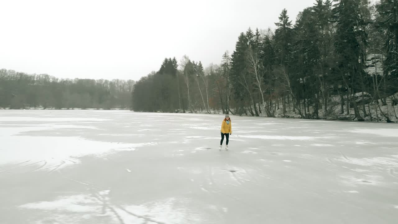 tiro de dron de una mujer joven patinando sobre hielo en un lago congelado solo