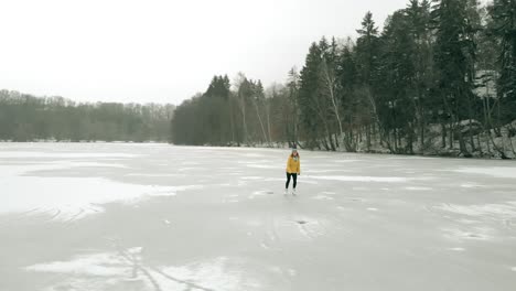 Tiro-De-Dron-De-Una-Mujer-Joven-Patinando-Sobre-Hielo-En-Un-Lago-Congelado-Solo