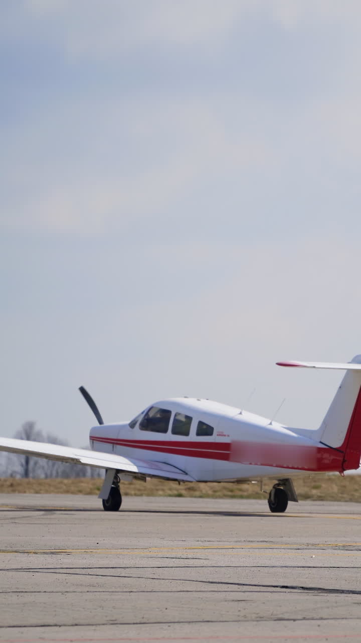 Little white airplane with red lines rides buy the empty aerodrome. Aircraft is taking off. Vertical video