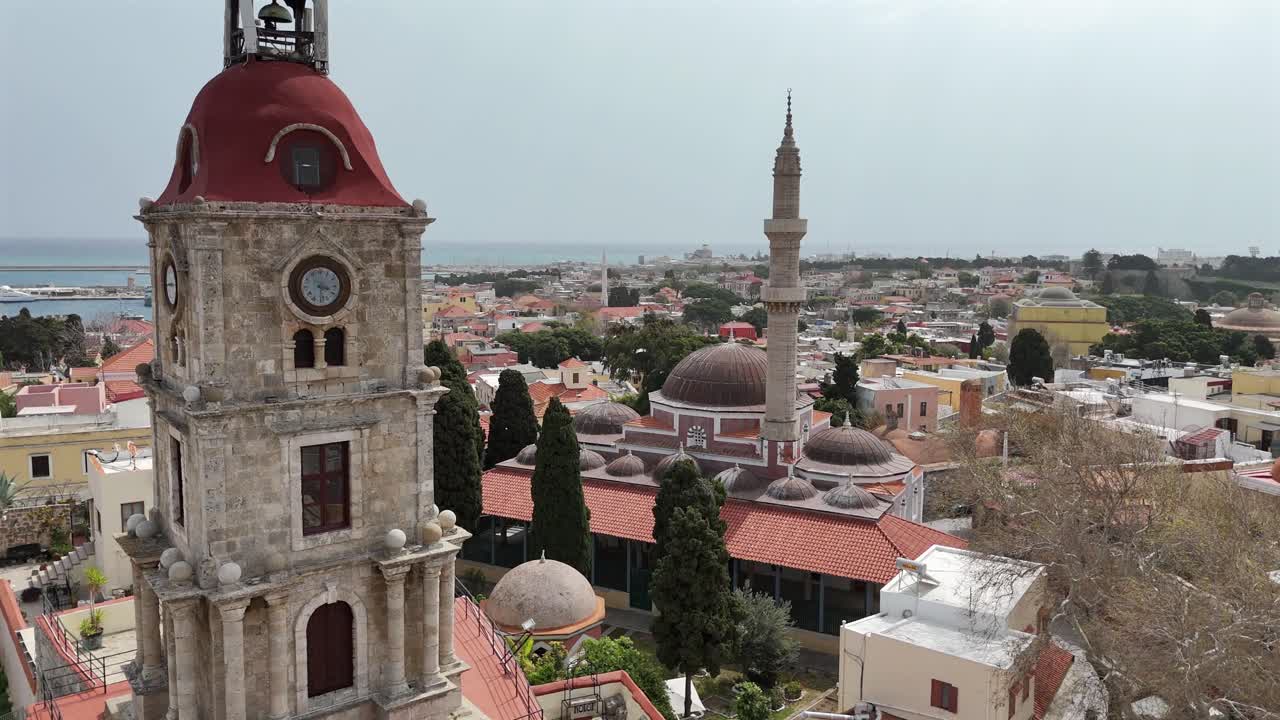 Aerial view forward towards Medieval Clock Tower (Roloi Clock Tower) and The Suleyman Mosque in the city of Rhodes in Rhodes island in Greece.Harbor and old town at the background on a sunny day.
