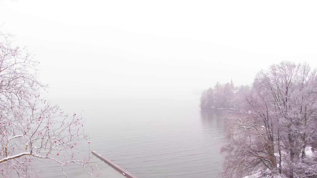 Misty Winter Lake Scene with Snowy Trees and Pier