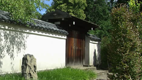 Roofed-gate,-tiled-wall-and-decorative-rock-in-a-Japanese-courtyard