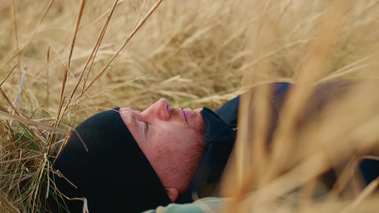 A Tranquil Moment of Serenity: A Man Relaxing Amidst Tall Grass in Nature, Embracing the Calmness of His Surroundings and Taking a Break from Daily Life's Fast Pace for Reflection and Peace