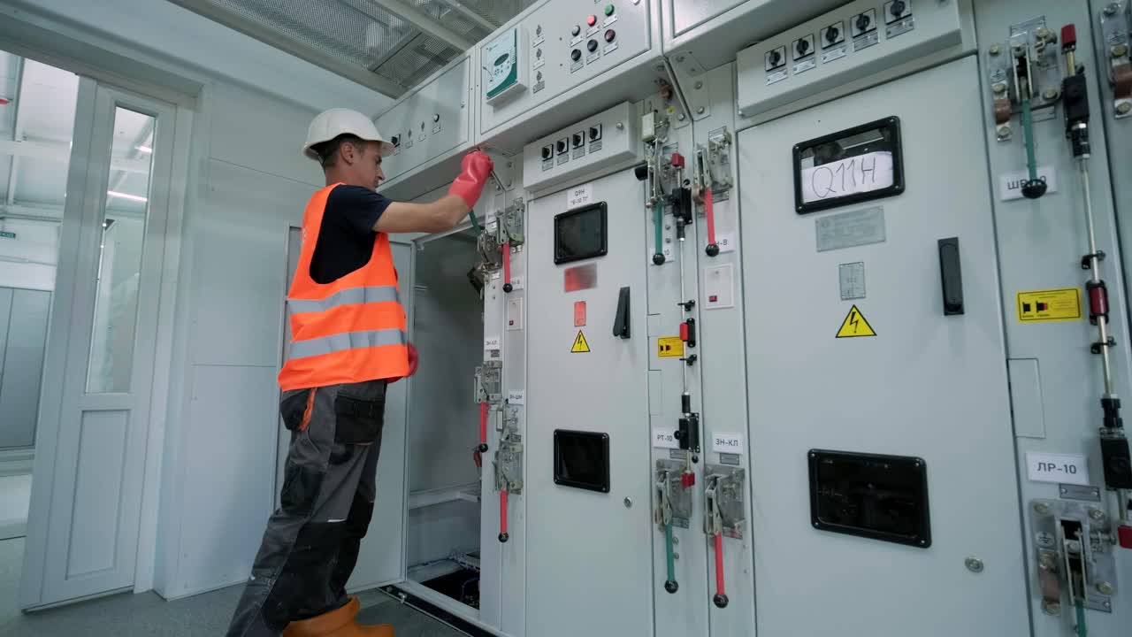 el ingeniero eléctrico que trabaja comprueba la tensión de corriente eléctrica y la sobrecarga en la parte delantera del gabinete del centro de carga o de la unidad de consumo para el mantenimiento en la sala principal del sistema de distribución de energía.